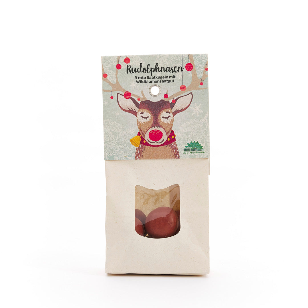 Papiertüte mit Aufdruck eines Rentiers und dem Text "Rudolphnasen – 8 rote Saatkugeln mit Wildblumensaatgut", darunter ein Sichtfenster mit roten Saatkugeln.