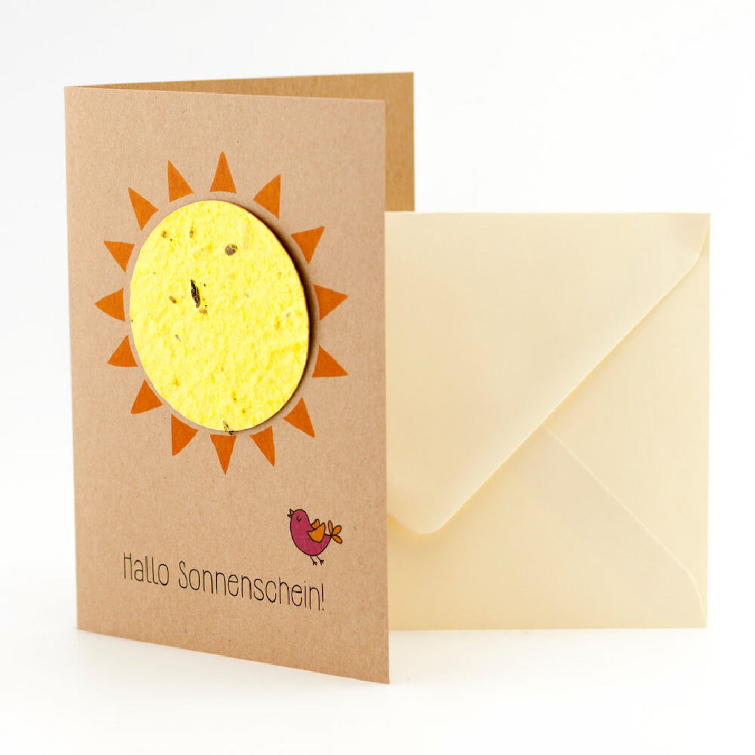 Grußkarte mit Sonnenmotiv und der Aufschrift "Hallo Sonnenschein!" neben einer cremefarbenen Umschlag.