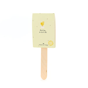 Gelbe Karte mit Küken-Illustration und Text "Hurra, du bist da!" auf einem Holzstab.