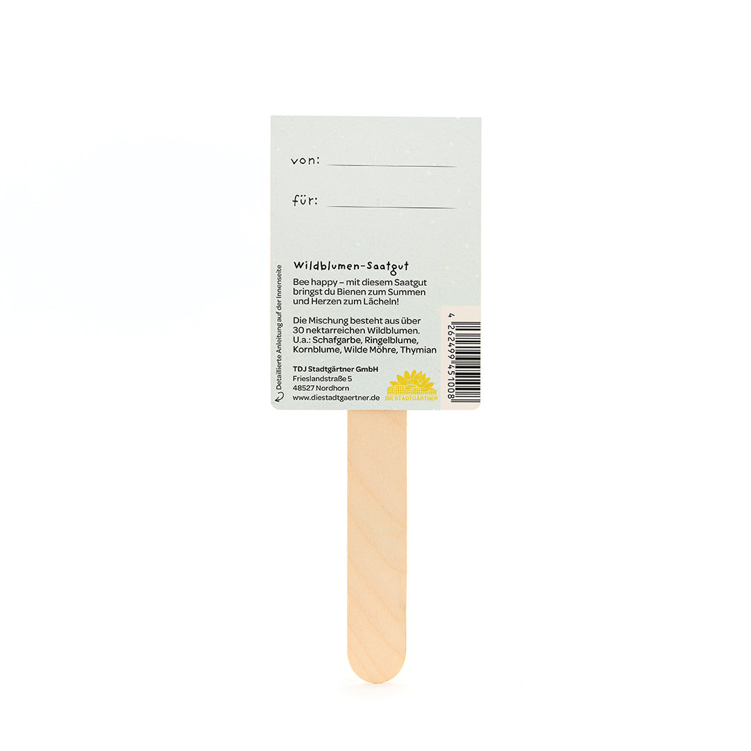 Rückseite eines Samentütchens mit Holzstab, auf dem Angaben über Wildblumen-Saatgut und Platz für „von:“ und „für:“ stehen.