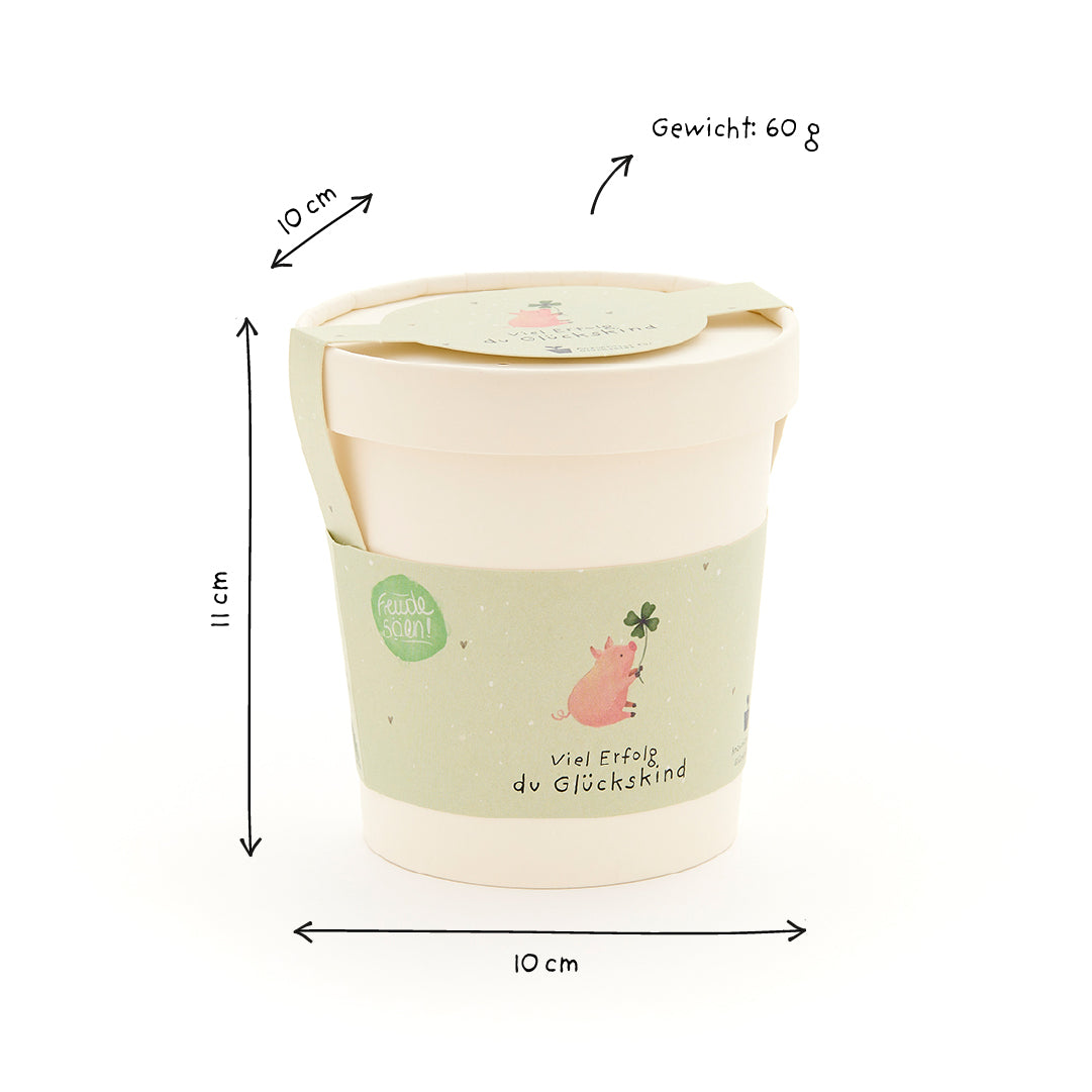 Becher mit grünem Etikett, Schweinchen und Kleeblatt, Maße 11 cm hoch, 10 cm Durchmesser, Gewicht 60 g.