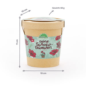 Pappbecher mit Blumenmotiv und der Aufschrift „Deine Schokoblümchen“, daneben Maße (10 cm Durchmesser, 11 cm Höhe) und Gewicht (60 g) auf Deutsch angegeben.