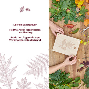 Zwei Hände halten eine Holzplatte mit einer filigranen Lasergravur eines Blattes, umgeben von verschiedenen bunten Herbstblättern und Bastelmaterialien; daneben Text mit Informationen zu Lasergravur, Messing-Flügelmuttern und Produktion in Deutschland.