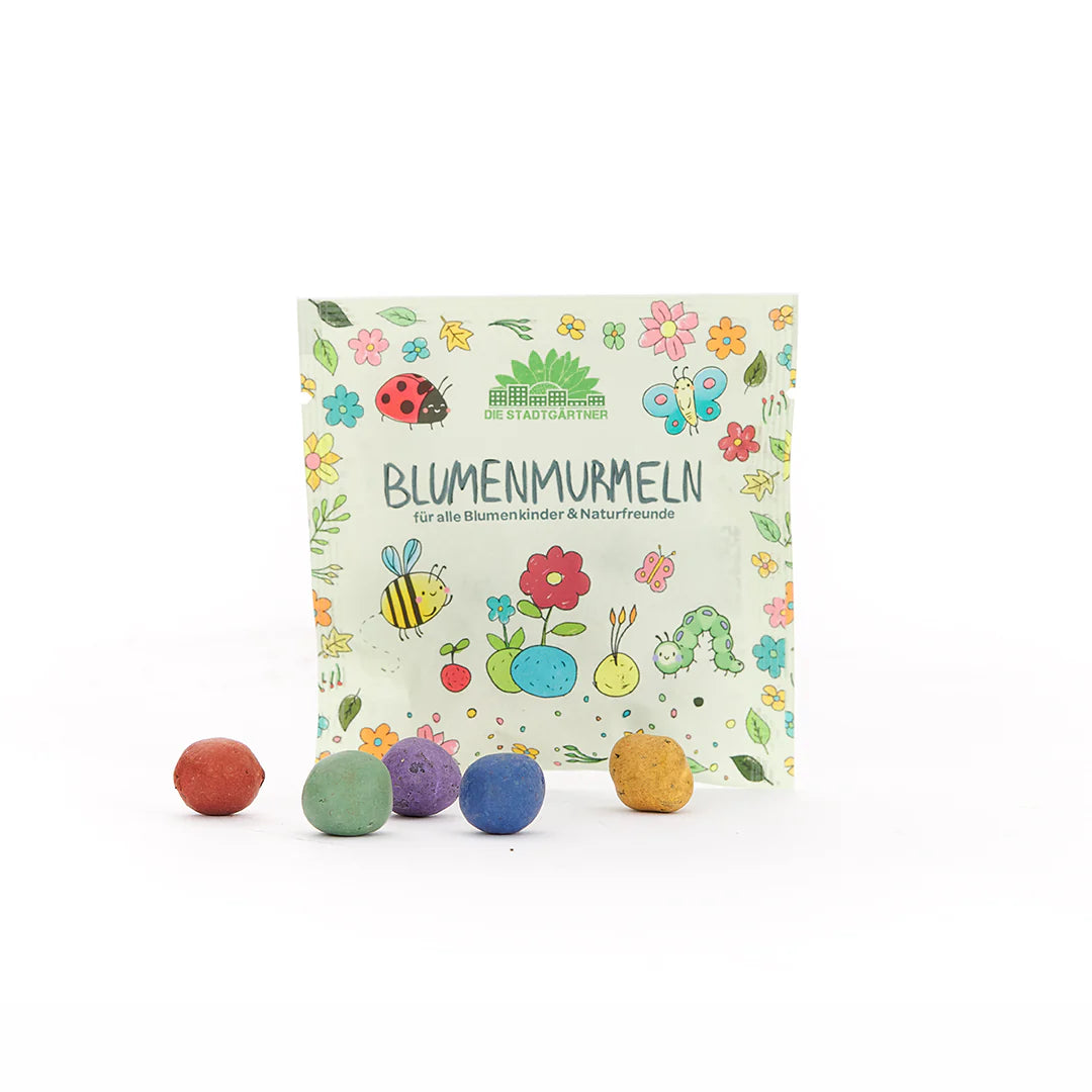 Paket mit der Aufschrift "Blumenmurmel" und bunten Blumenmurmeln davor auf weißem Hintergrund.