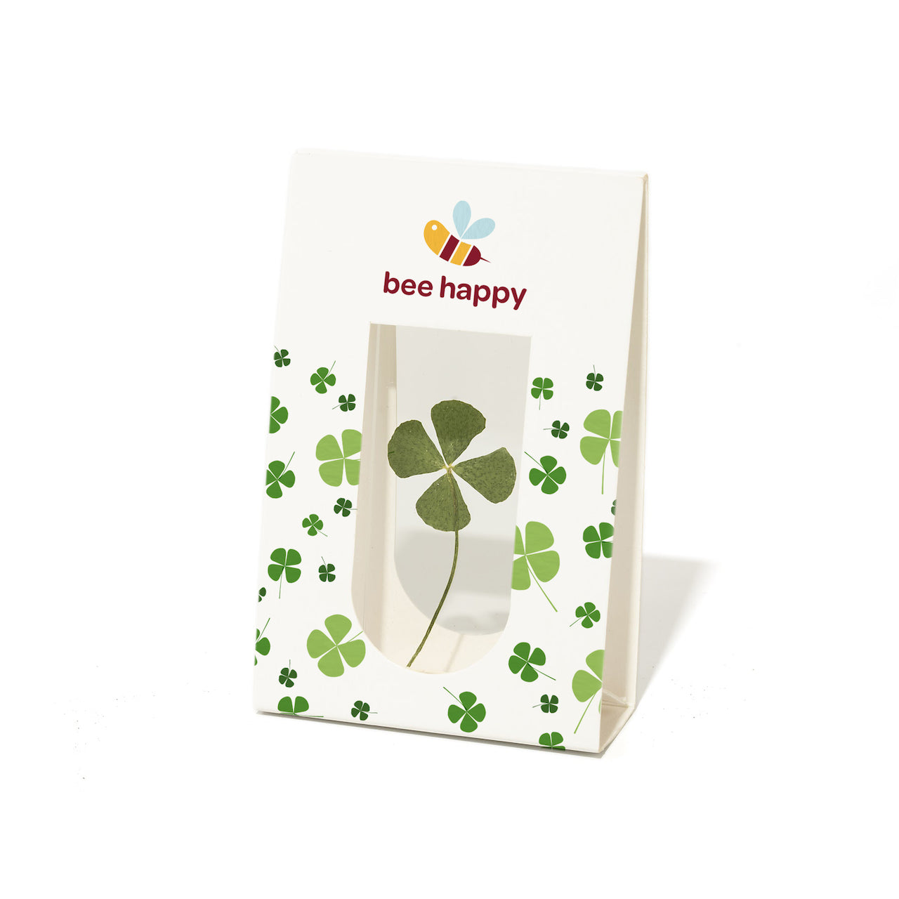 Papiertüte mit vierblättrigem Kleeblatt und dem Text "bee happy" sowie einer Bienenillustration.