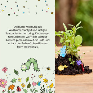 Bunte Illustration mit Text über Wildblumensaatgut und Saatpapierformen für Kinder, daneben ein kleiner Pflanzenhaufen mit bunten Papier-Schmetterlingen und Blumen im Boden.