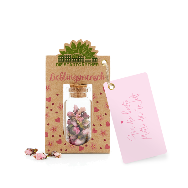 Geschenkanhänger mit der Aufschrift 'Lieblingsmensch' und ein kleines Glasfläschchen mit getrockneten Blüten, daneben eine rosa Karte mit der Nachricht 'Für dich'"